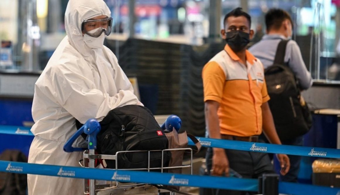 Seorang penumpang (kiri) yang mengenakan alat pelindung diri (APD) mengantre untuk check-in penerbangan di Bandara Internasional Kuala Lumpur (KLIA) di Sepang pada 29 November 2021, ketika negara-negara di seluruh dunia menutup perbatasan dan memperbarui pembatasan perjalanan sebagai tanggapan terhadap penyebaran variasi virus corona Covid-19 baru yang sangat bermutasi yang dijuluki Omicron. (Foto oleh Mohd RASFAN / AFP) (Foto oleh MOHD RASFAN/AFP via Getty Images)