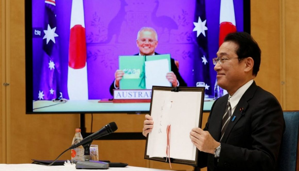 Japan's Prime Minister Fumio Kishida, (right), and Australia's Prime Minister Scott Morrison show off signed documents during their video signing ceremony of the bilateral reciprocal access agreement at Kishida's official residence in Tokyo, Japan, on January 6, 2022 [Issei Kato/Pool via Reuters]