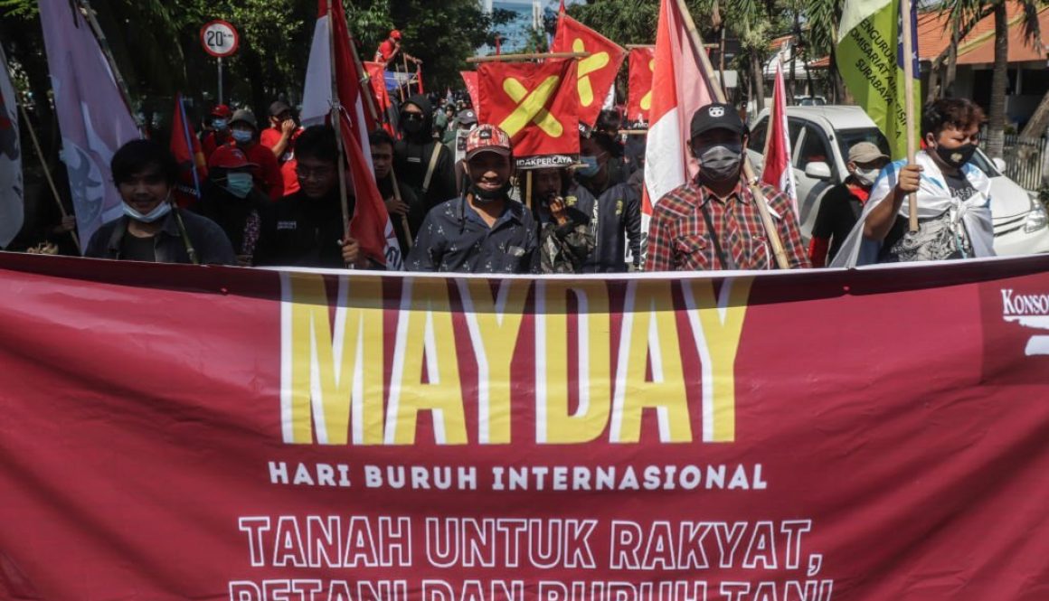 Para pekerja dan aktivis yang mengenakan masker dan membawa plakat menggelar demonstrasi memperingati Hari Buruh Internasional (Foto oleh Suryanto/Anadolu Agency via Getty Images)