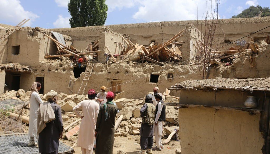 Orang-orang Afghanistan berdiri di dekat puing-puing sebuah bangunan setelah gempa berkekuatan 6,1 SR mengguncang provinsi perbatasan Paktika, Afghanistan pada 22 Juni 2022. (Foto oleh Bilal Guler/Anadolu Agency via Getty Images)