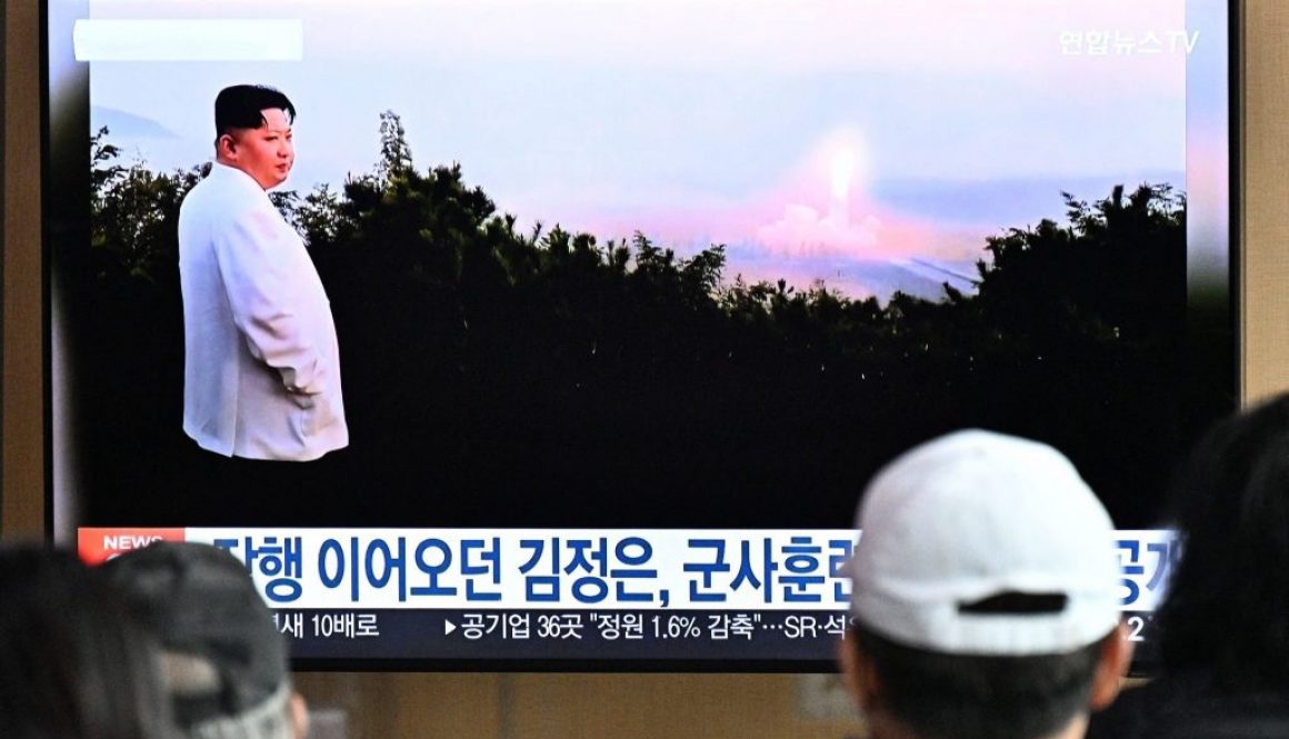 Orang-orang duduk di dekat televisi yang menayangkan siaran berita dengan rekaman file pemimpin Korea Utara Kim Jong Un mengawasi uji coba rudal, di sebuah stasiun kereta api di Seoul pada 10 Oktober 2022. (Foto oleh ANTHONY WALLACE/ AFP melalui Getty Images)