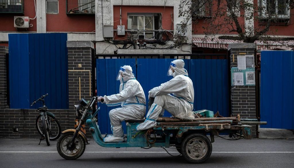 Pekerja pengendalian epidemi mengenakan alat pelindung untuk mencegah penyebaran COVID-19 saat mereka melewati komunitas yang dikunci pada 22 November 2022 di Beijing, Cina. (Foto oleh Kevin Frayer/Getty Images)