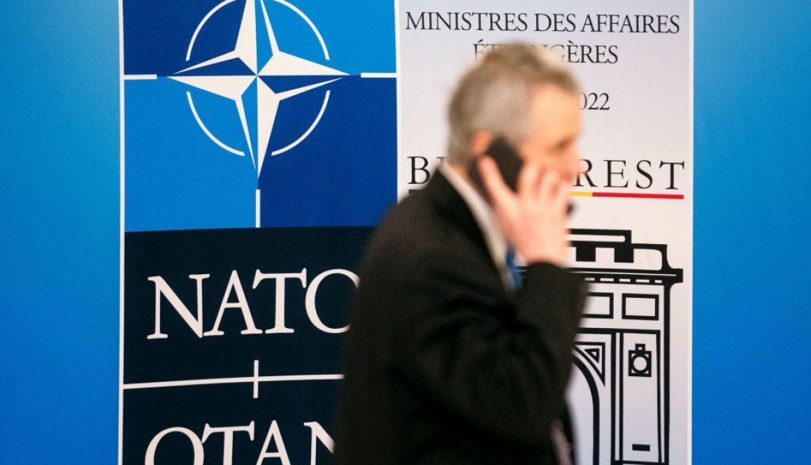 Seorang pria berjalan melewati logo NATO saat pertemuan para Menteri Luar Negeri NATO di Bukares, Rumania, pada 30 November 2022. (Foto oleh ANDREI PUNGOVSCHI/AFP via Getty Images)