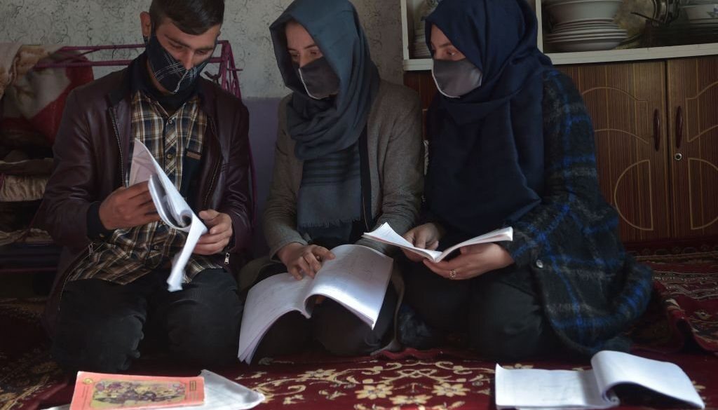 Seorang siswi membaca buku dengan saudara laki-lakinya Hamid (kiri) di rumah mereka di Kabul. Wanita sekarang dilarang kuliah di Afghanistan yang dikuasai Taliban, tempat mereka terus-menerus dilucuti dari kebebasan mereka selama setahun terakhir. (Foto oleh AHMAD SAHEL ARMAN/AFP via Getty Images)