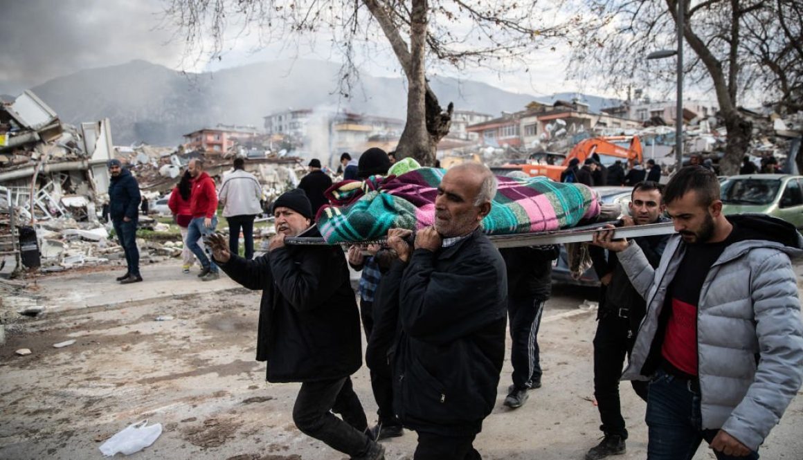 Orang-orang membawa mayat di dekat bangunan yang runtuh pada 06 Februari 2023 di Hata Turki. (Foto oleh Burak Kara/Getty Images)