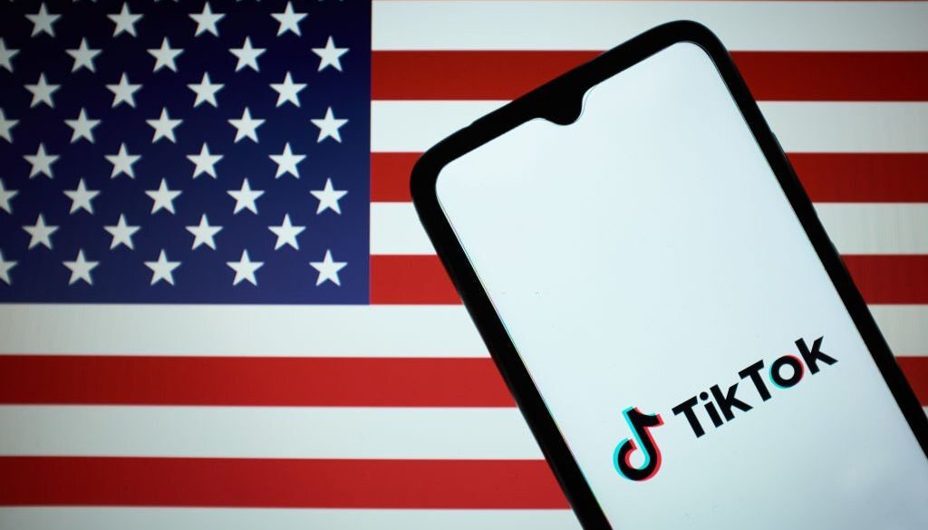 Dalam ilustrasi foto ini terlihat logo TikTok yang terpampang di layar smartphone dengan latar belakang bendera Amerika Serikat di Athena, Yunani pada 9 Maret 2023. (Ilustrasi foto oleh Nikolas Kokovlis/NurPhoto via Getty Images)