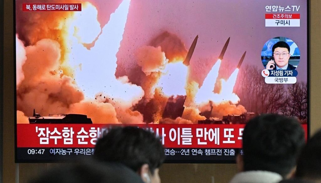 Orang-orang berdiri di dekat televisi yang menayangkan siaran berita dengan rekaman file uji coba rudal Korea Utara, di sebuah stasiun kereta api di Seoul pada 14 Maret 2023. (Foto oleh ANTHONY WALLACE/AFP via Getty Images)