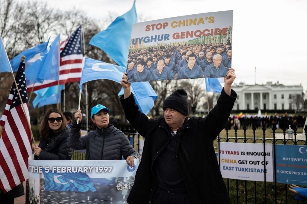 Orang-orang mengangkat bendera dan tanda selama protes di Washington, DC pada 5 Februari 2023, menandai peringatan 26 tahun pembantaian Ghulja 1997 di Kota Ghulja, di provinsi Xinjiang, China. (Foto oleh ANDREW CABALLERO-REYNOLDS/AFP via Getty Images)