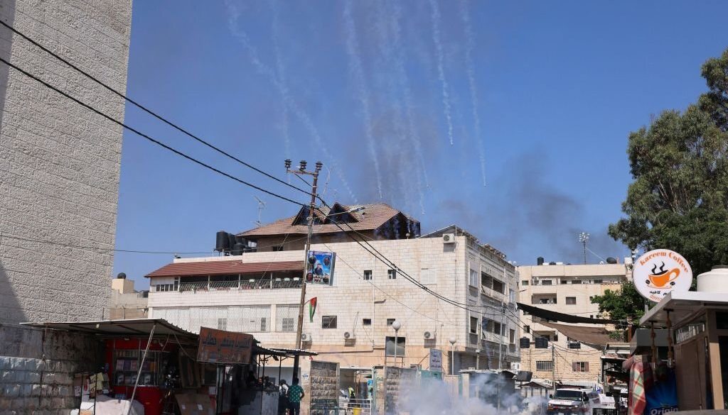 Orang-orang melarikan diri dari tabung gas air mata yang jatuh selama operasi militer Israel yang sedang berlangsung di kota Jenin di Tepi Barat yang diduduki pada 4 Juli 2023. (Foto oleh JAAFAR ASHTIYEH/AFP via Getty Images)
