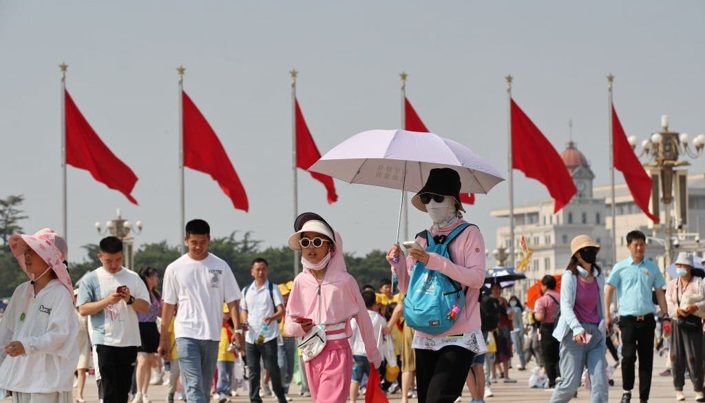 Turis menggunakan payung dan pakaian pelindung untuk berlindung dari sinar matahari di Lapangan Tiananmen saat suhu kota mencapai 40 derajat celsius pada 24 Juni 2023 di Beijing, China. (Foto oleh Wang Xin/VCG via Getty Images)
