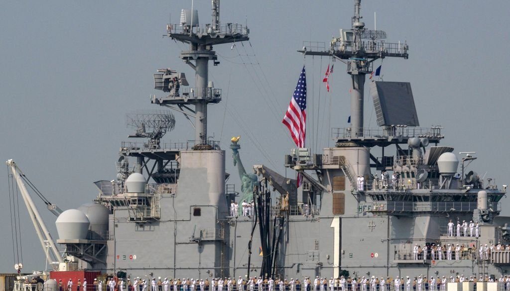 Pelaut dan Marinir AS berdiri di dek penerbangan USS Bataan, kapal serbu amfibi kelas Wasp, saat melewati Patung Liberty selama Pekan Armada di Pelabuhan New York pada 24 Mei 2023. (Foto oleh ANGELA WEISS / AFP) (Foto oleh ANGELA WEISS/AFP melalui Getty Images)