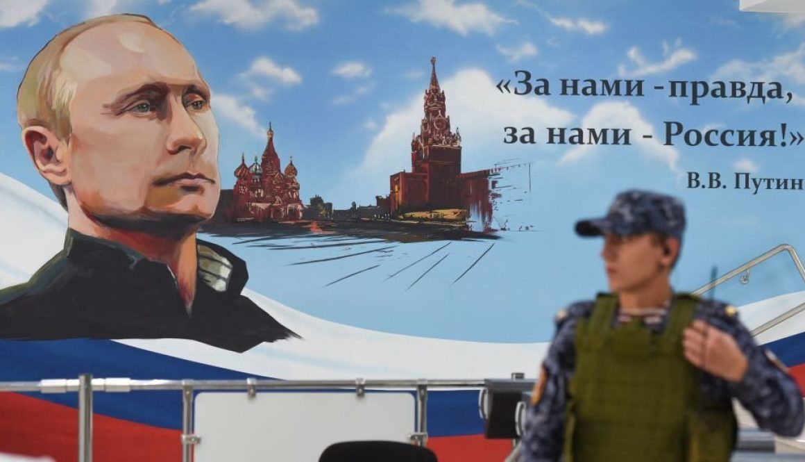 A Russian policeman stands next to a wall bearing an image of Russia's President Vladimir Putin and Moscow's Kremlin at a polling station during local elections organised by the Russian-installed authorities in Donetsk, Russian-controlled Ukraine, on September 8, 2023. (Photo by AFP) (Photo by -/AFP via Getty Images)