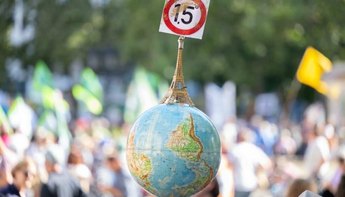 A globe with a miniature Eiffel Tower and the 1.5-degree target of the Paris climate agreement is carried by a man at the demonstration in front of the Alte Oper in Frankfurt (Photo by Boris Roessler/picture alliance via Getty Images)