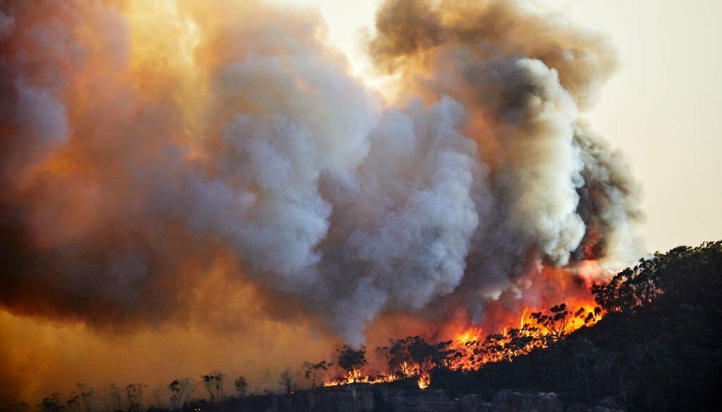 Kebakaran hutan, kebakaran hutan dengan nyala api dan awan asap yang menyinari matahari saat senja di punggung gunung, Blue Mountains, Australia (Foto stok via Getty Images)