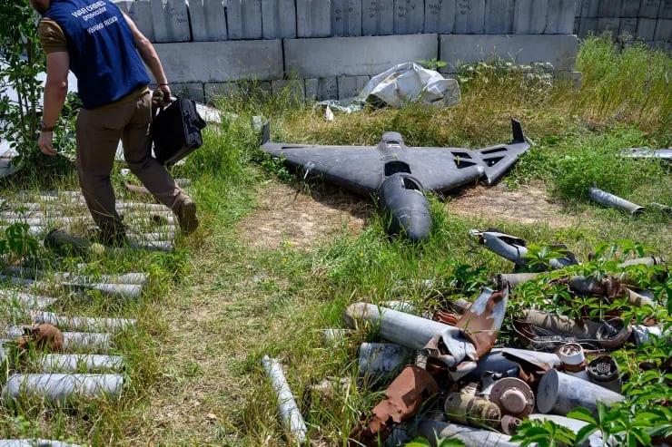 A war crimes prosecutor stands next to the wreckage of a Russian Shahed-136 drone, developed by Iran and known as Geran-2 in Russia, in Kharkiv on July 30